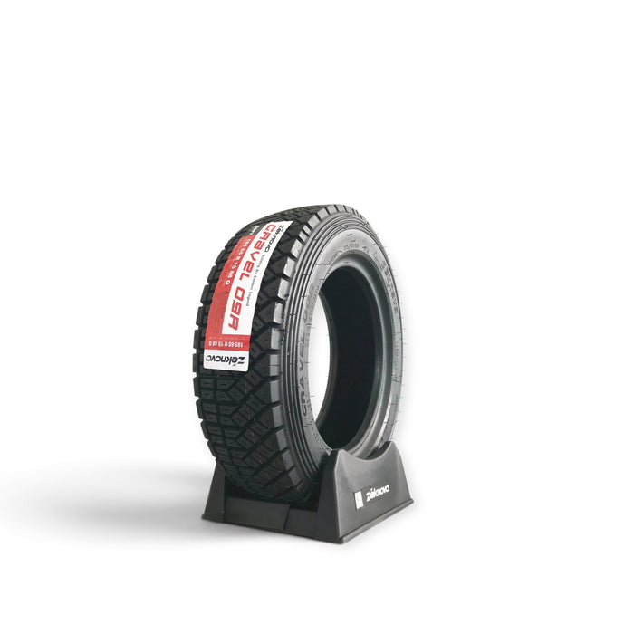 Lunaticsco Zeknova Gravel 09R rally competition tire with asymmetric tread pattern on a black display stand.